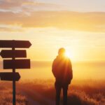 Man standing by a sign and looking out at different paths while the sun shines in front of him